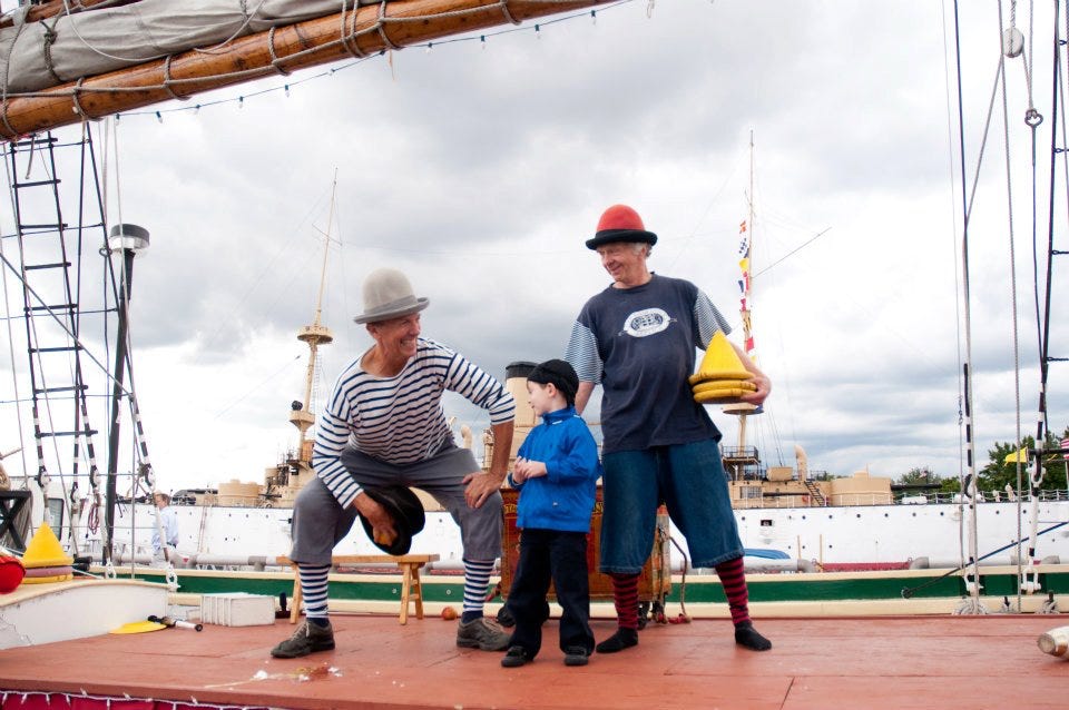 2 jugglers with volunteer and hats on a boat deck