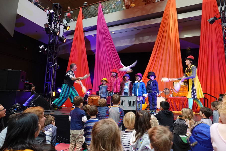 2 club jugglers passing around a line of audience volunteers